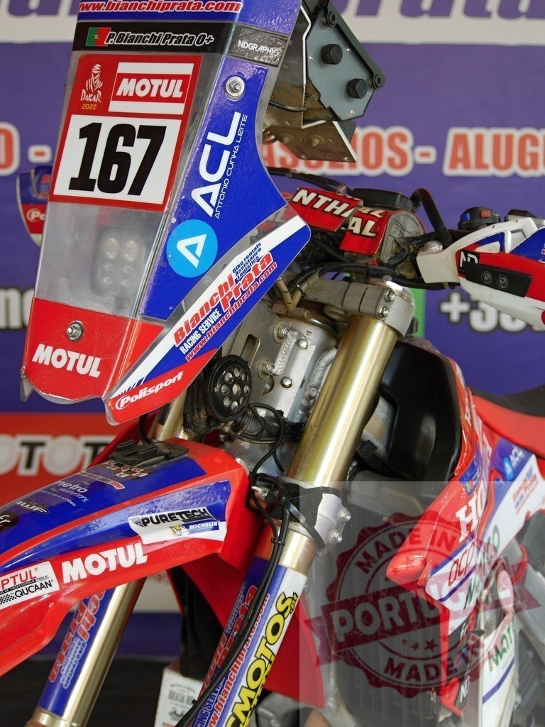 Honda crf 450x rally motorcycle featuring motul and bianchi prata sponsorships | Close-up of a Honda CRF 450X rally motorcycle showcasing Motul and Bianchi Prata sponsorships, highlighting the vehicle's preparation for an off-road racing event - Realized with Pictrs.com