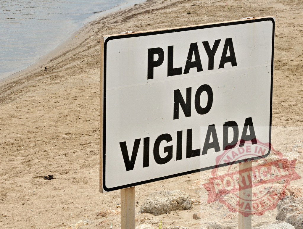 Unguarded beach warning sign in Spanish on sand | Warning sign Playa no vigilada communicating danger on an unsupervised beach - Realized with Pictrs.com