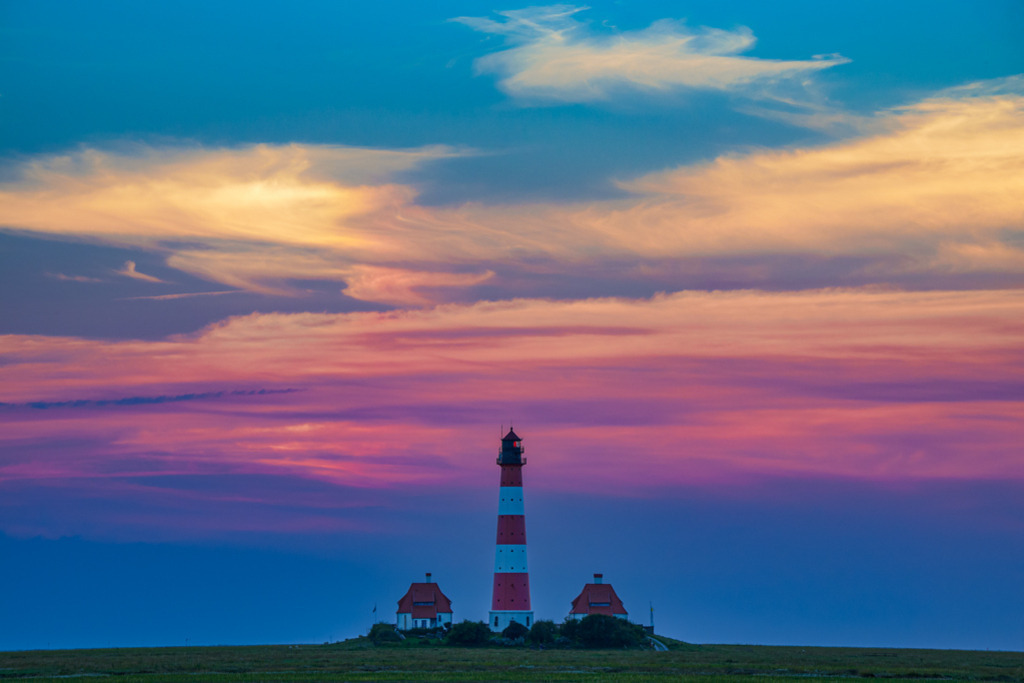 Leuchtturm Westerheversand | Das Abendlicht lässt Wolken über dem Leuchtturm Westerheversand erglühen. Die Fotografie gibt einen Charakterzug von Schleswig-Holstein wieder, sie weckt das Empfinden für Weite, Raum, faszinierender Stille an der See. — Auflösung des Originals: 6015 x 4010 px. - Realisiert mit Pictrs.com