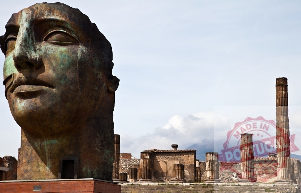 Igor Mitoraj head sculpture in Pompeii ruins with Mount Vesuvius | Bronze head sculpture by Igor Mitoraj standing among ancient Roman ruins with Mount Vesuvius - Realized with Pictrs.com