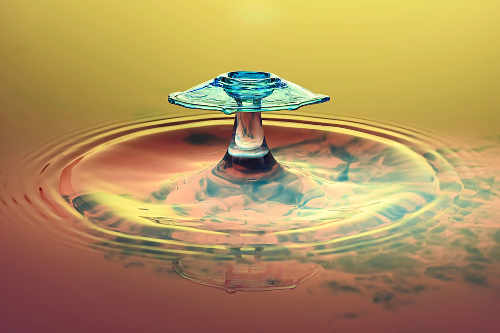 Farbenfroher schrim Tropfen | Ein faszinierender Wassertropfen, eingefangen im exakten Moment des Aufpralls, zeigt eine perfekte Symmetrie und brillante Farben. Dieses Makrofoto illustriert die Schönheit und Präzision der Hochgeschwindigkeitsfotografie – ein visuelles Spiel aus Wasser, Licht und Bewegung.