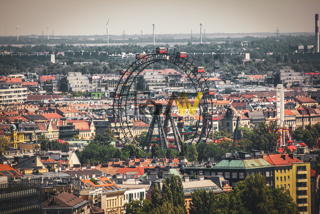Das Wiener Riesenrad mitten in Wien-Panorama von oben | Das Bild zeigt das Wiener Riesenrad im Prater in Wien, Österreich. Es ist ein bekanntes Wahrzeichen der Stadt. Das Riesenrad wurde 1897 eröffnet und ist das älteste in seiner Bauweise noch bestehende Riesenrad der Welt.  - Realisiert mit Pictrs.com