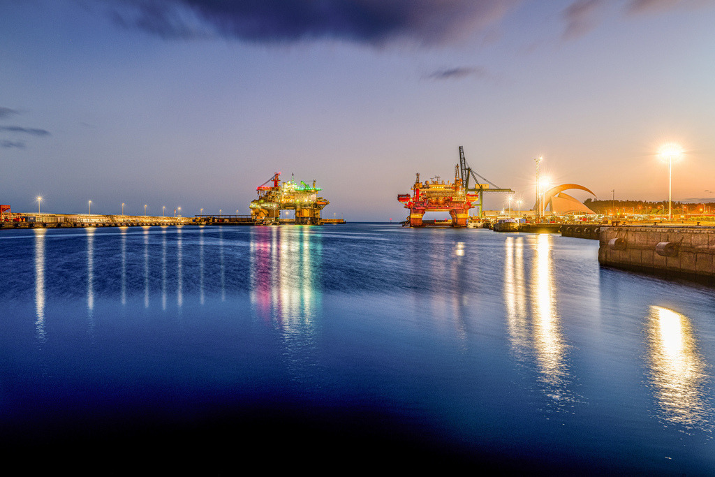 Bohrinseln in Santa Cruz de Tenerife bei Nacht|Fuerteventura | Das Bild zeigt zwei beleuchtete Bohrinseln im Hafen von Santa Cruz de Tenerife bei Nacht.Standort: Santa Cruz de Tenerife, Kanarische Inseln, Spanien.Grund: Bohrinseln liegen oft für Wartungsarbeiten, Reparaturen oder Zwischenstopps in Häfen.Beleuchtung: Die Langzeitbelastung am Abend lässt das Wasser ruhig und spiegelnd erscheinen - Realisiert mit Pictrs.com