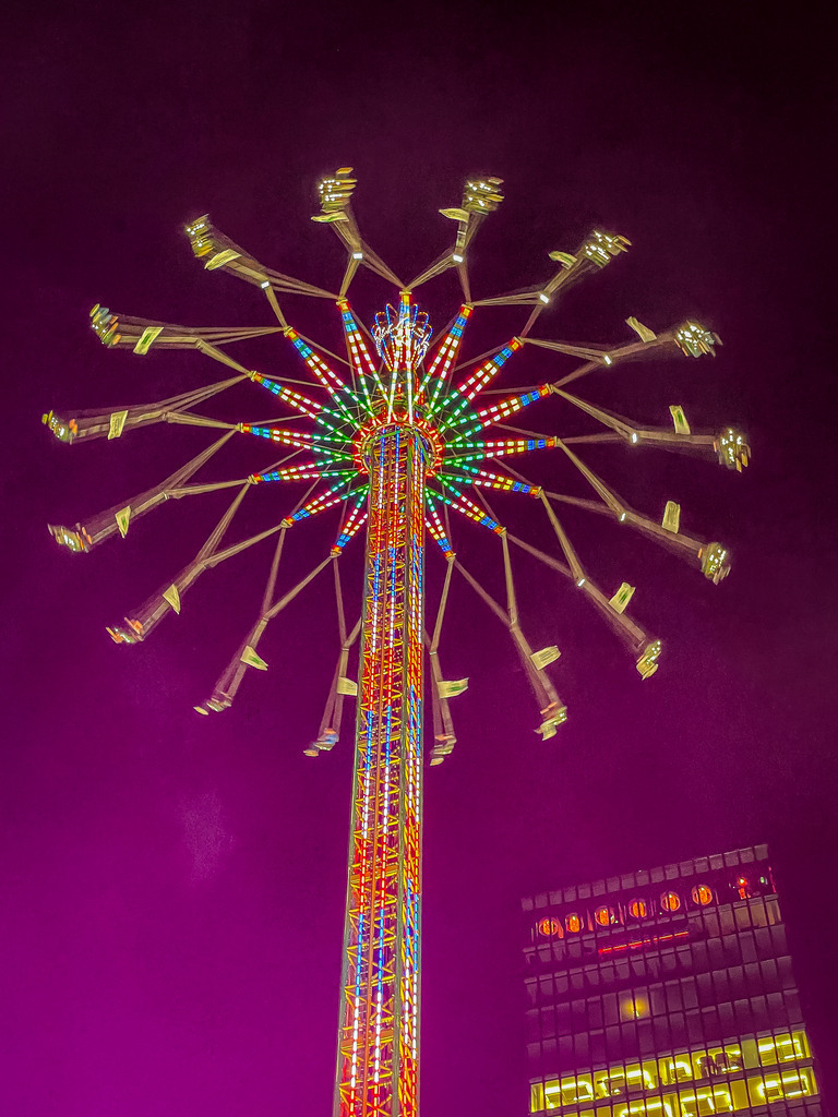 Basel Messeturm – Star Flyer Kettenkarussell bei Nacht | Exklusive Architektur- und Nachtfotografie aus Basel: Dieses High-End Wandbild zeigt das gigantische Kettenkarussell Star Flyer in geometrischer Symmetrie vor dem violetten Nachthimmel. Im Hintergrund leuchtet die markante Fassade des Basler Messeturms. Ein minimalistisches, farbgewaltiges Kunstwerk für moderne Räume. Perfekt als edler Galariedruck auf Acrylglas oder Alu-Dibond. - Realisiert mit Pictrs.com