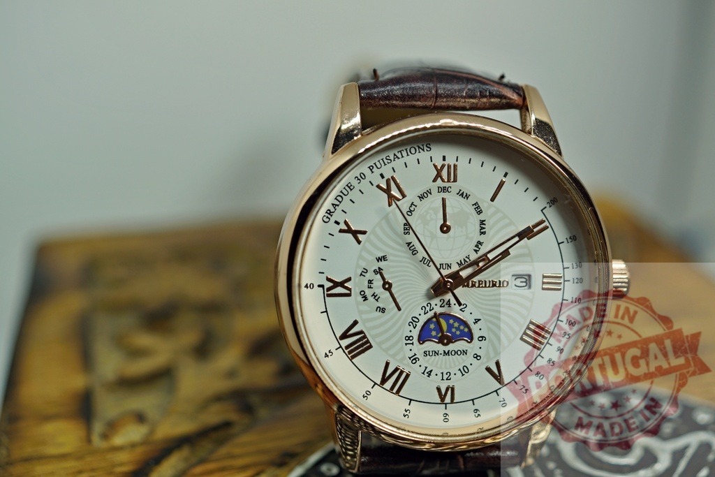 Luxury gold wrist watch showing moon phase and calendar | Golden wrist watch displaying time, date and moon phase on a wooden surface - Realisiert mit Pictrs.com