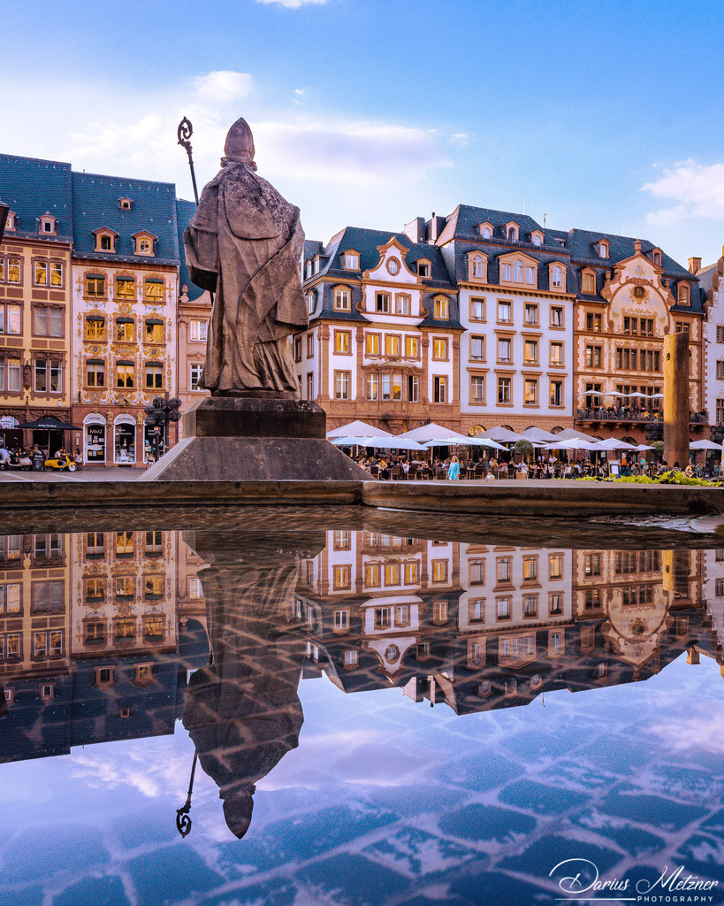 Wasserspiegelung mit dem heiligen Bonifatius  | Der heiligen Bonifatius vor dem Mainzer Dom schaut auf die Markthäuser, während der Maskenbrunnen eine kurze Pause einlegt und diese Spiegelung erlaubt.
