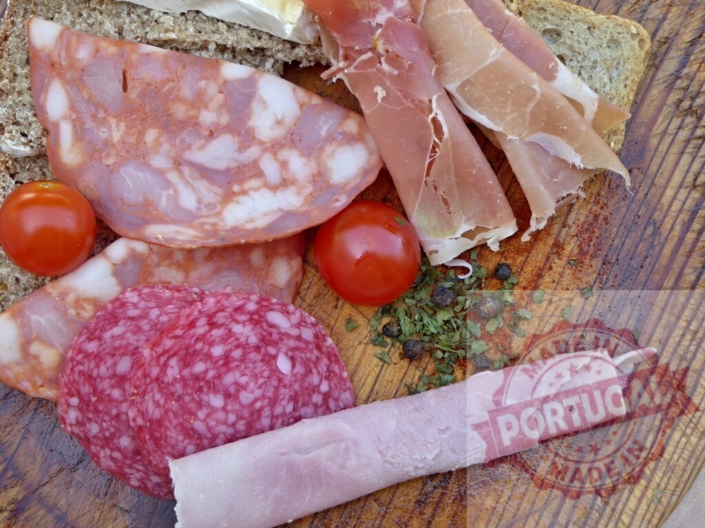 Rustic charcuterie board with sliced meats and vegetables | Charcuterie board presenting an assortment of sliced meat, salami, prosciutto, ham, and fresh tomatoes - Realized with Pictrs.com