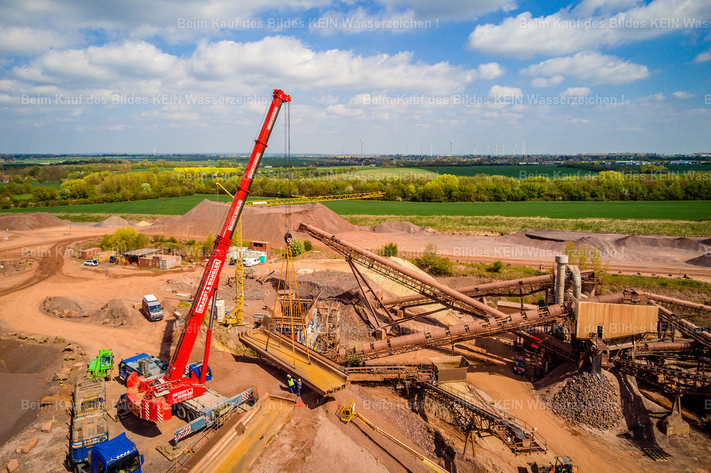 Mammendorf Brecher 2 Drohne-0026 | Blick aus der Drohne auf den Steinbruch bei Mammendorf während der Errichtung einer neuen technischen Anlage. Im Mittelpunkt der Aufnahme steht ein großer Kran, der eine Brückenkonstruktion einschweben lässt.Das Luftbild dokumentiert damit einen besonderen Moment innerhalb der Bauphase: Die neue Anlage entsteht direkt im laufenden Steinbruchbetrieb, während ein wichtiges Bauteil mit schwerem Hebegerät an seine vorgesehene Position gebracht wird.Aus der Drohnenperspektive werden sowohl die Dimension des Krans als auch die Größe der einzuschwebenden Brücke und ihre Einbindung in die neue Anlage deutlich. Gleichzeitig bleibt der Steinbruch als industrieller Rohstoffstandort im Hintergrund erkennbar.Eine Momentaufnahme aus der Baustellendokumentation, die einen Arbeitsschritt festhält, der kurze Zeit später bereits wieder Geschichte ist. - Realisiert mit Pictrs.com