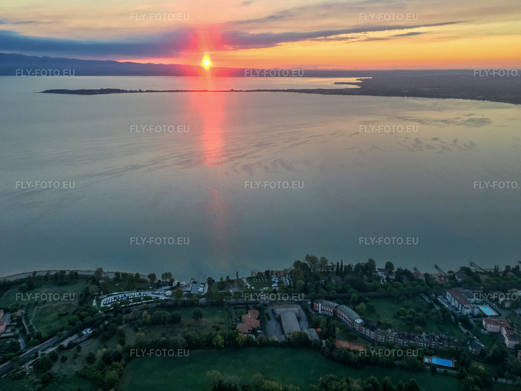 Vue aérienne: Lever du soleil à Barche Bellandi sur le lac de Garde à Desenzano del Garda dans le département Brescia, Italie. Photo: IMG-134975.jpg prise le 23/09/2022 par Werner Riehm/FLY-FOTO.eu – Résolution de l'original: 3998 x 2998 px