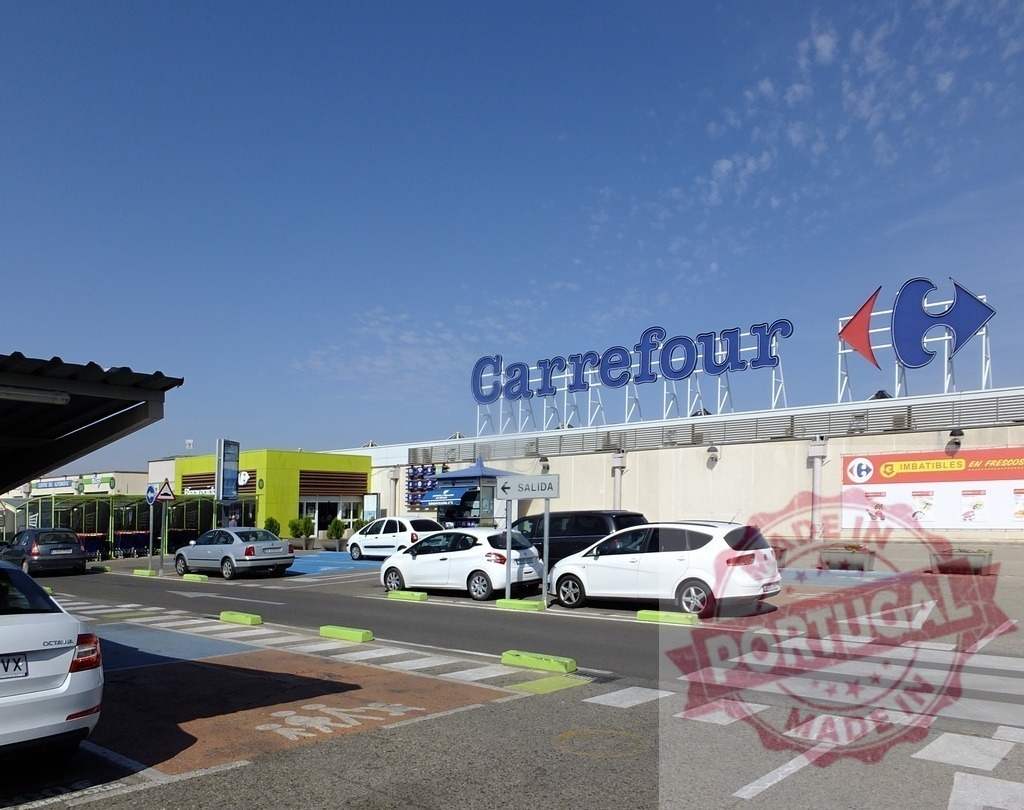 Carrefour supermarket facade with parking lot and cars | Carrefour supermarket entrance with cars parked under a clear blue sky, illustrating retail commerce - Realisiert mit Pictrs.com