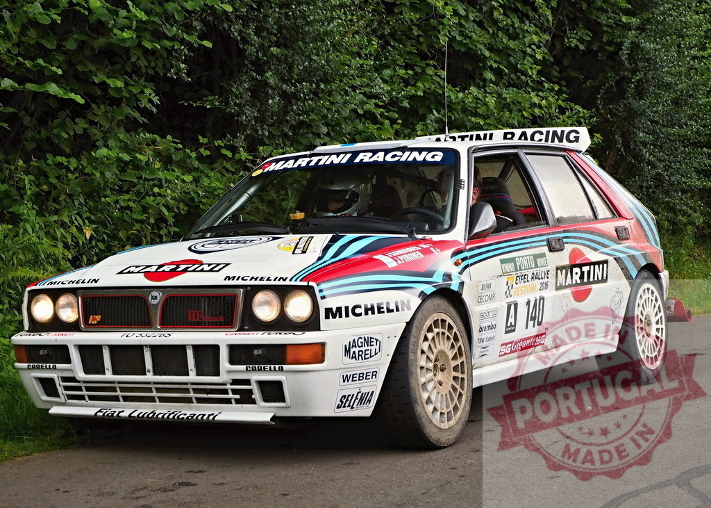 Lancia Delta Integrale rally car competing on a forest road | Lancia Delta Integrale rally car with Martini Racing livery driving on a road - Realized with Pictrs.com