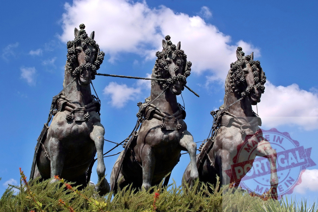Three bronze horse sculptures against blue sky. Espana - Cadiz | Three ornate bronze horse statues, decorated with grapevines, standing against a blue sky with white clouds - Realized with Pictrs.com