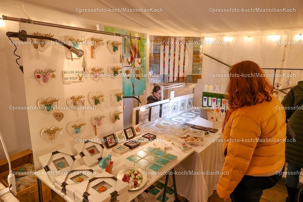 Wup12122501033 | 12.12.2026, Wuppertal, Weihnachtsmarkt Haus Schloss Lüntenbeck. Besucher betrachen die Auslage eines Kunsthandwerkers