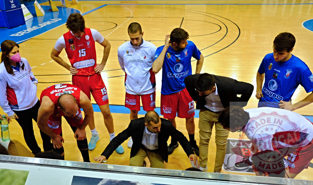 Basketball team huddling with coach discussing strategy during a game | Basketball coach discussing strategy with players during a timeout on the court - Realized with Pictrs.com