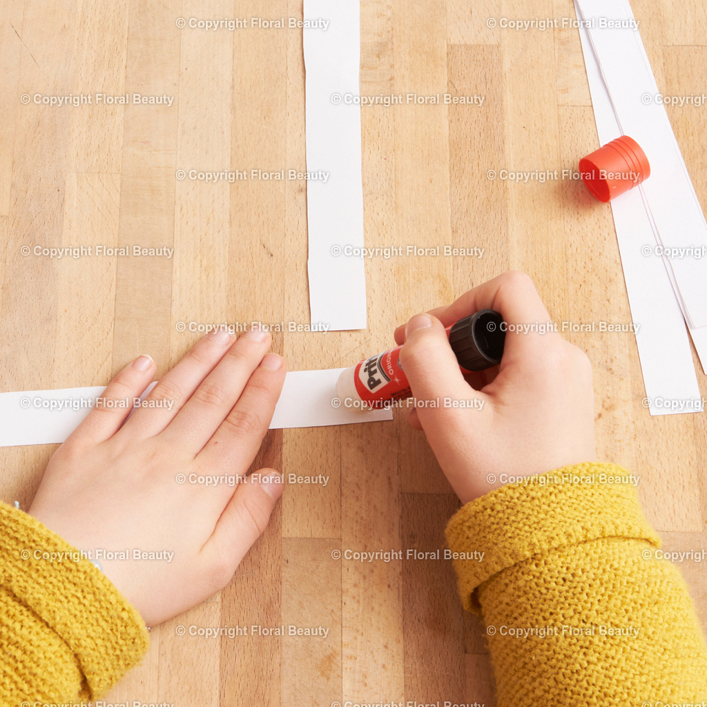 Hexentreppe aus Papier basteln | Papier in 2 cm breite Streifen schneiden. Mit Kleber rechtwinklig fixieren. Abwechselnd Streifen über Streifen legen und andrücken. Abschließend zusammenkleben. - Realisiert mit Pictrs.com