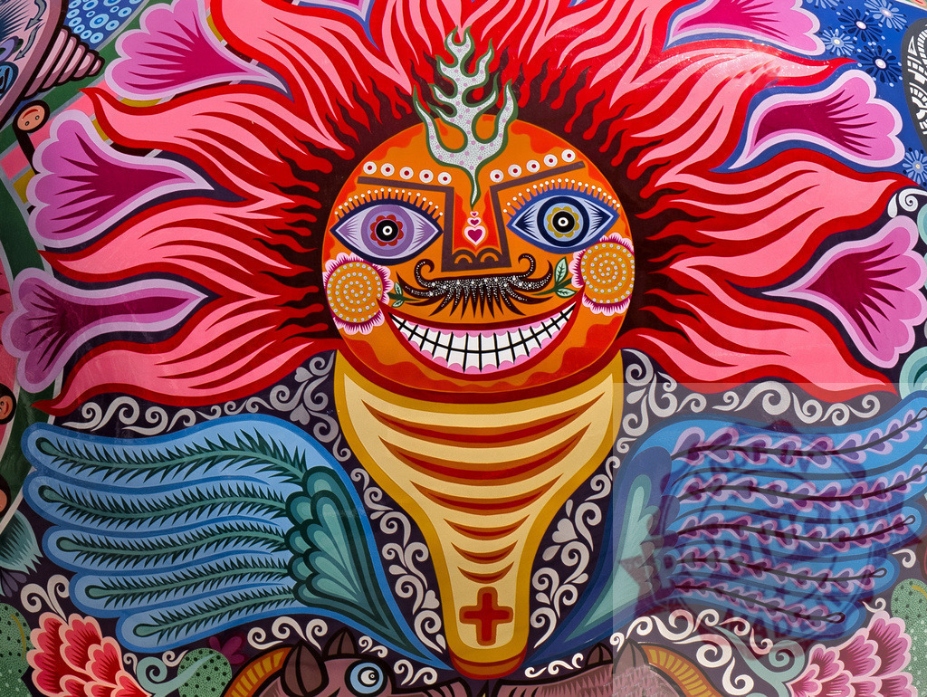 Colorful Mexican folk art sun face vibrant mural | Stylized sun motif painted with bright colors and traditional Huichol folk art patterns - Realized with Pictrs.com