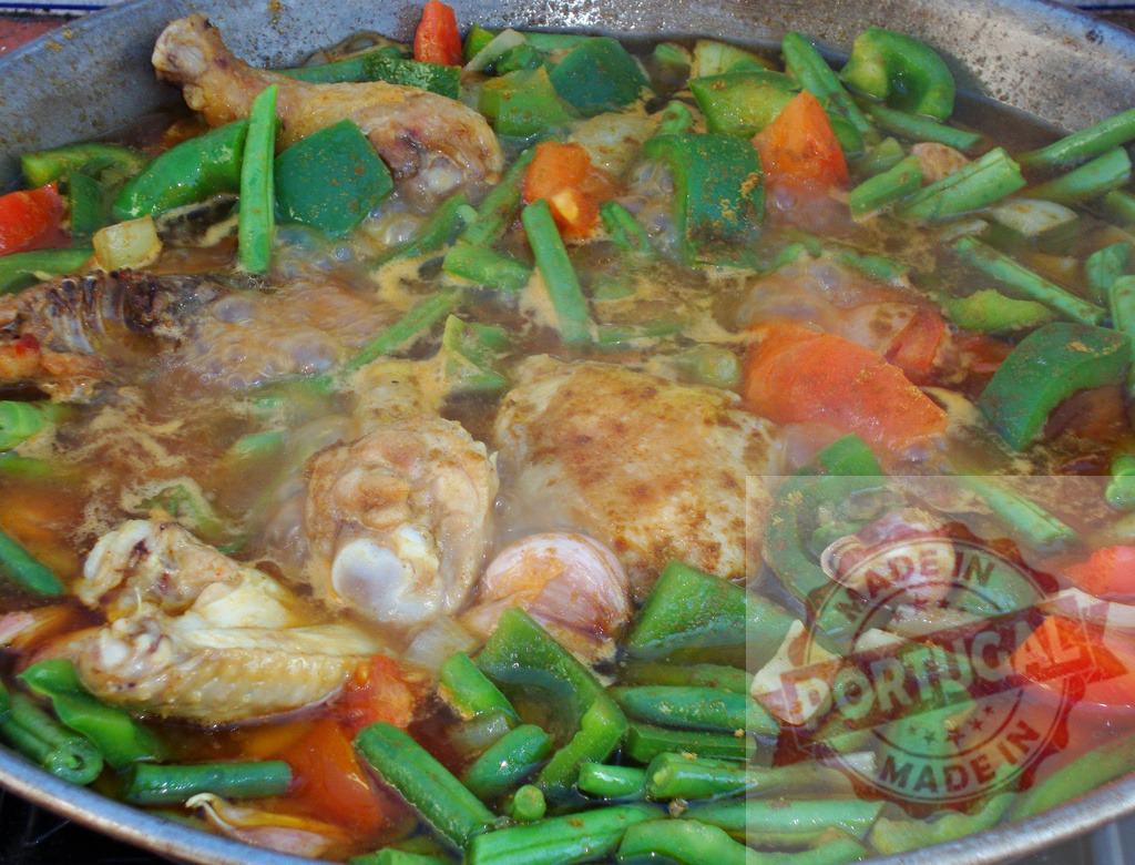 Chicken paella cooking with fresh vegetables in a pan | Chicken and vegetables simmering in a pan, preparing a delicious Spanish paella - Realisiert mit Pictrs.com
