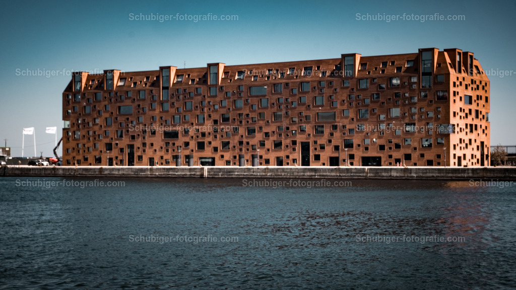 Pier 47 Pakhuset Kopenhagen | Pier 47 ist ein Bürogebäude am Langelinie-Pier in Kopenhagen. Es wurde von Lundgaard & Tranberg entworfen und ist im Besitz von ATP Ejendomme.Das Gebäude ist aus rotem Ziegelstein erbaut, inspiriert von Lagerhäusern aus dem 19. Jahrhundert wie dem nahe gelegenen Dahlerup Warehouse. Das Äußere wird von den unregelmäßig sechseckigen und unregelmäßig angeordneten Fenstern dominiert. Das Gebäude wurde mit Blick auf nachhaltige Lösungen entworfen und wurde von der DGNB in Gold zertifiziert. Zu den nachhaltigen Lösungen gehören natürliche Belüftung und Grundwasserkühlung. - Realisiert mit Pictrs.com