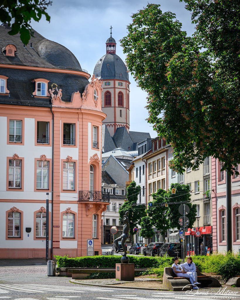 St Stephan und der Osteiner Hof in Mainz | Im Hintergrund sieht man den Turm der St. Stephan Kirche in Mainz, die weit über die Grenzen der Stadt hinaus für ihre Fenster von Marc Chagall bekannt ist. Im Vordergrund ist ein Teil des Osteiner Hofs zu sehen.
