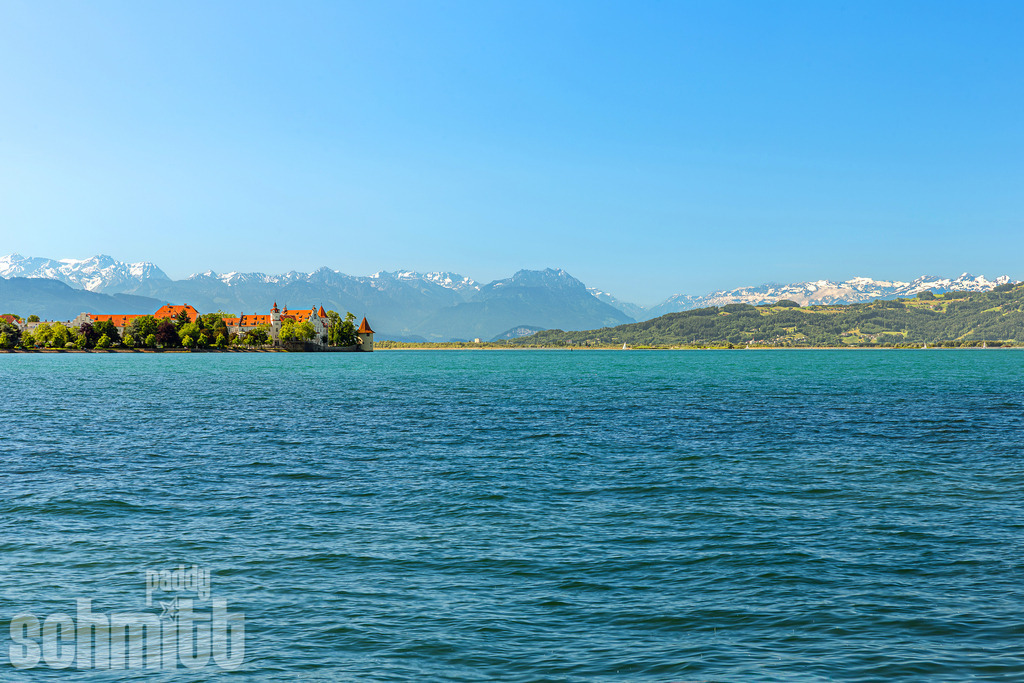 Frühling am Bodensee mit Blick auf die Lindauer Insel und die Berge | Im frischen Licht des Frühlings eröffnet sich ein idyllischer Blick über den Bodensee auf die Insel Lindau und die dahinterliegende Bergkulisse. Zartes Grün, klares Wasser und die majestätischen Alpen verbinden sich zu einer harmonischen und stimmungsvollen Landschaftsaufnahme. - Realisiert mit Pictrs.com