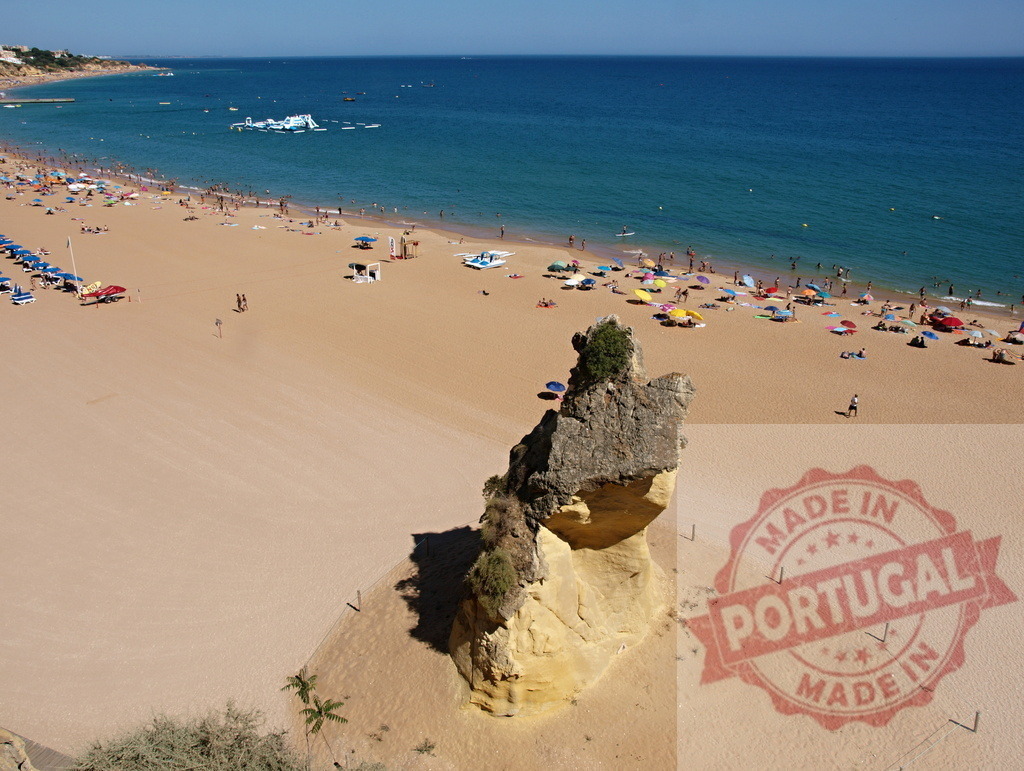 Beachgoers enjoying summer vacation in Algarve, Portugal | Crowded sandy beach with prominent rock formations and clear blue ocean on a sunny day - Realisiert mit Pictrs.com