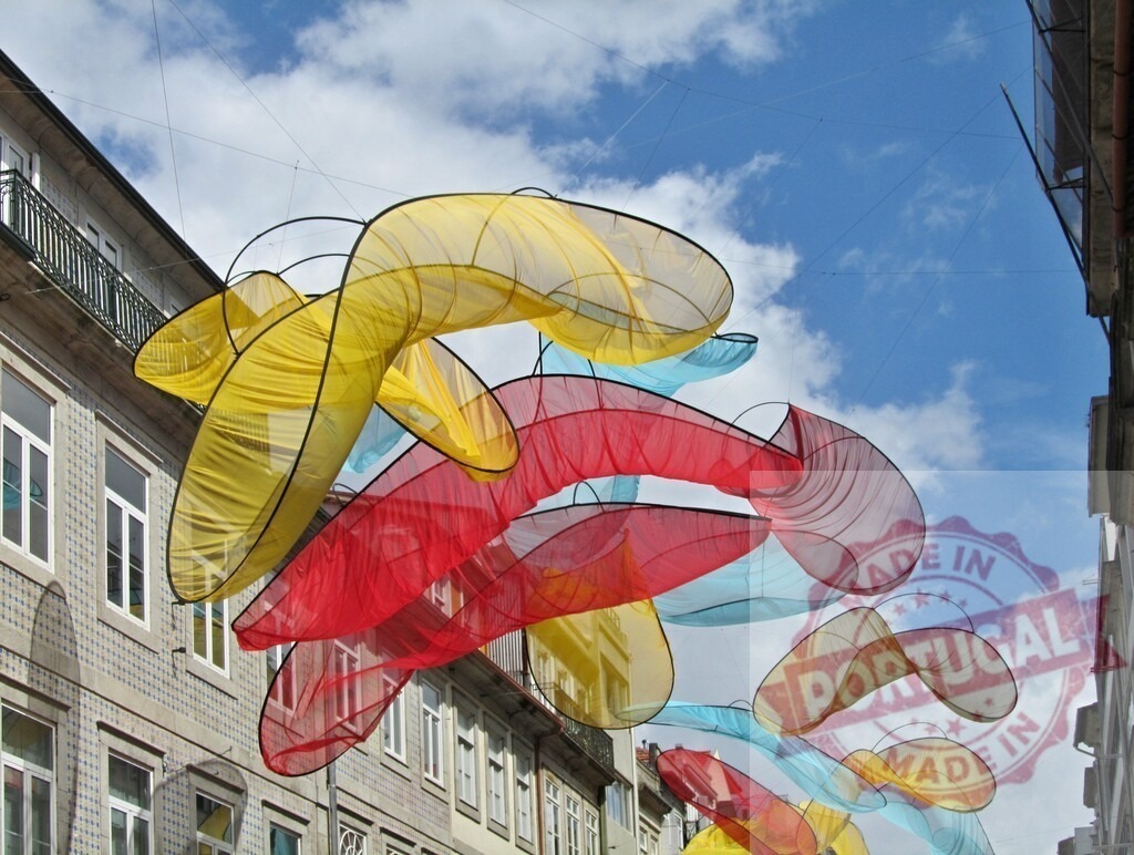 Colorful fabric sculptures creating a street art installation in Porto | Vibrant fabric installation decorating an urban street against a blue sky - Realized with Pictrs.com