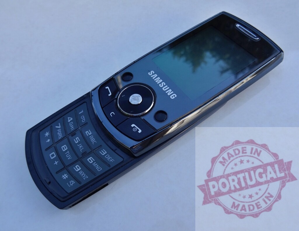 Old Samsung slider phone lying on a white surface | Classic Samsung mobile phone from the early 2000s showcasing its keypad and small screen - Realisiert mit Pictrs.com
