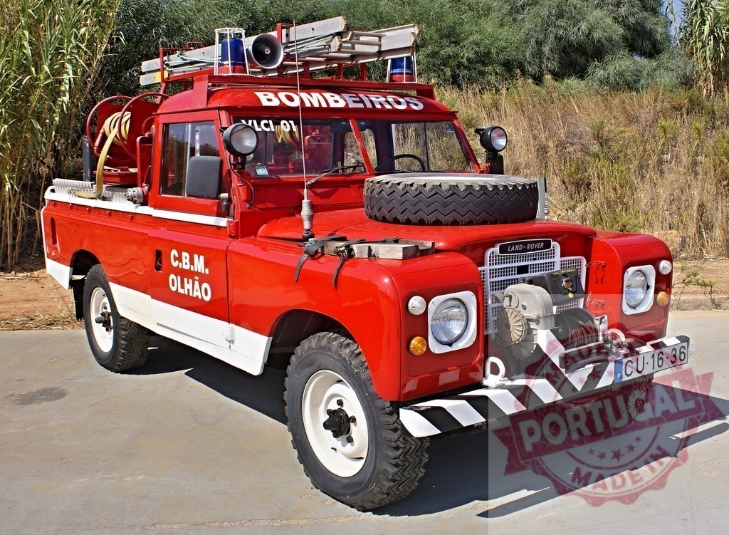 Red Land Rover Bombeiros firefighting vehicle in Portugal | Red Land Rover Series emergency vehicle parked by dry grass, preparing for fire rescue - Realisiert mit Pictrs.com