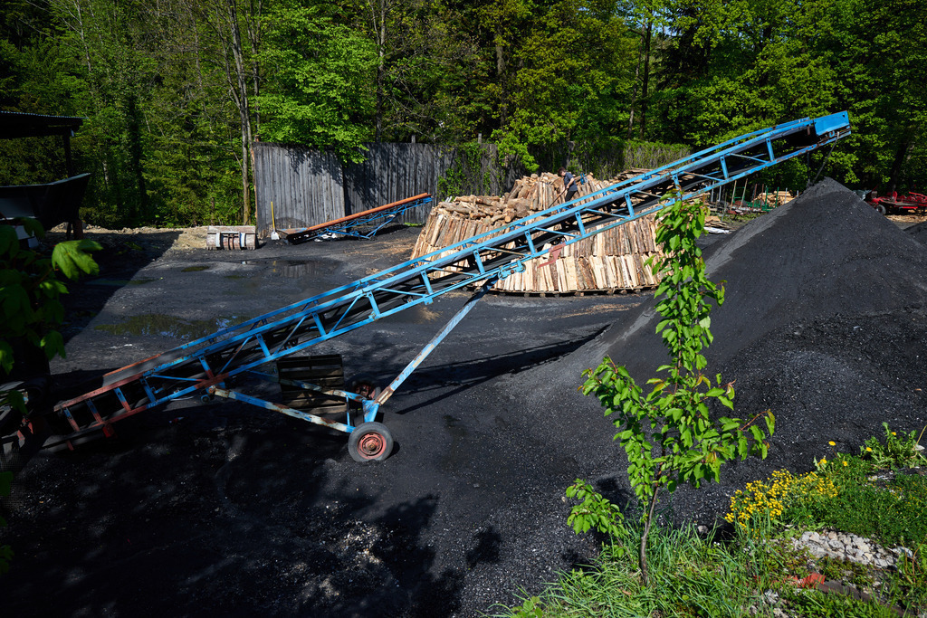 Blick auf den Kohlmeiler | Michelbach, Austria - May 08, 2019: Waldköhlerei Hochecker, die 2011 in das Nationale Verzeichnis des immateriellen Kulturerbes der UNESCO aufgenommen wurde, produziert noch echte Holzkohle; Blick auf den Kohlmeiler mit blauen Förderband. - Realisiert mit Pictrs.com
