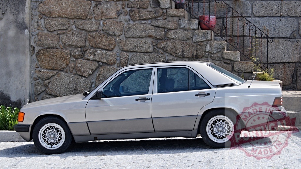 Mercedes-Benz 190 W201 classic car parking on street | Mercedes-Benz 190 W201 car parked on a paved street beside a stone wall - Realisiert mit Pictrs.com