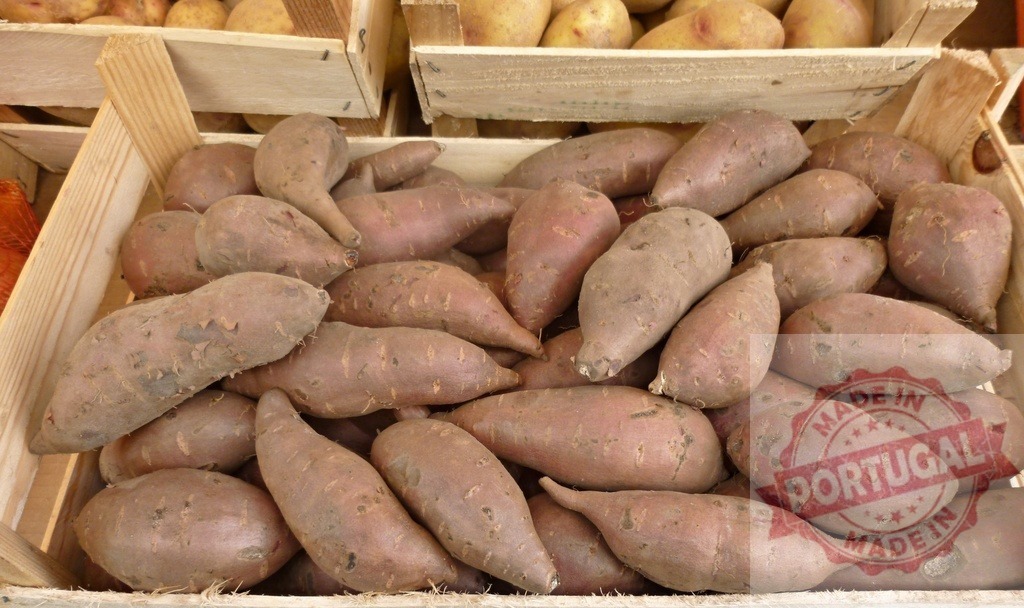 Sweet potatoes filling a wooden crate at market | Sweet potatoes filling a wooden crate, offering fresh produce from a local market - Realized with Pictrs.com