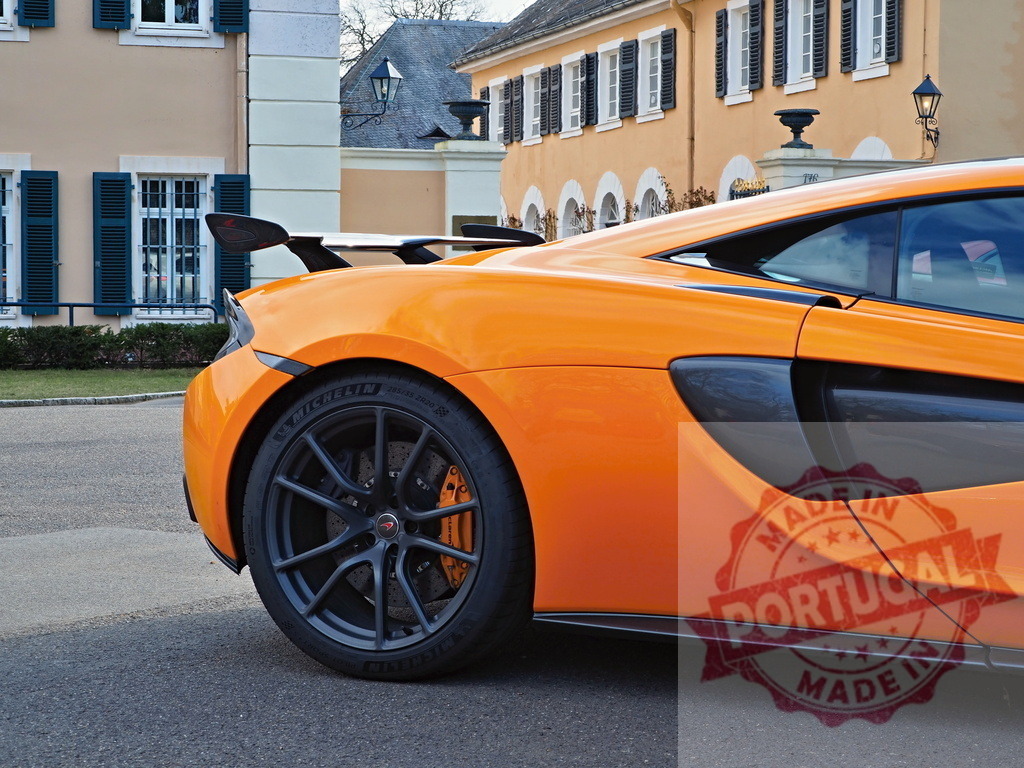 Orange McLaren 600LT supercar parked by luxury building | Orange McLaren 600LT parked on street, showcasing its rear aerodynamic spoiler and performance tire - Realized with Pictrs.com