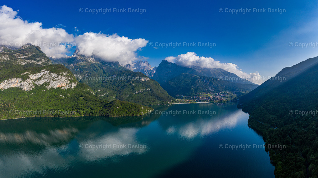 Wolkenspiegelung am Molvenosee – Molveno, Trentino, Italien | Der Molvenosee liegt ruhig zwischen den Bergen, während große Wolken über dem Tal ziehen und sich weich im Wasser spiegeln. Das tiefe Blau und die klare Bergkulisse geben dem Motiv eine elegante, fast meditative Stimmung.