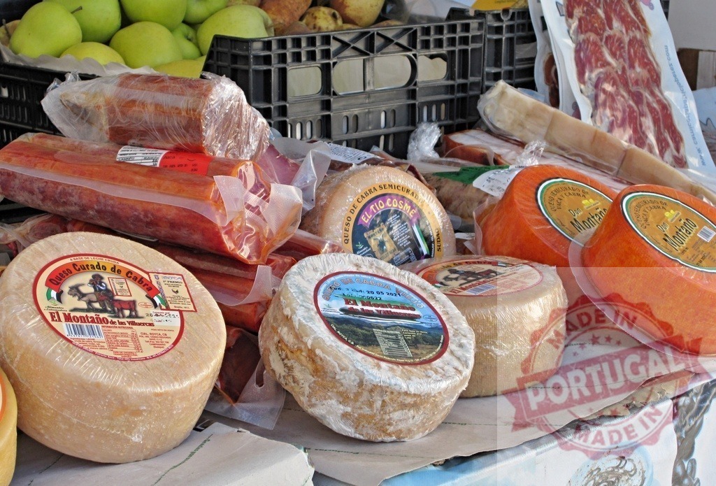 Spanish market stall selling cheese and cured meat | Artisan cheese wheels and charcuterie displaying at an outdoor Spanish market - Realized with Pictrs.com