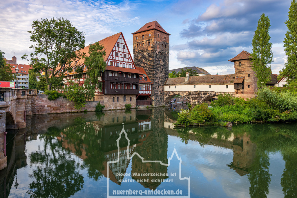 Sehenswürdigkeiten in Nürnberg | Der Weinstadel in Nürnberg, ein historisches Gebäude aus dem 15. Jahrhundert, ist eines der meistfotografierten Motive der Stadt. Mit seiner malerischen Fachwerkarchitektur und seiner Lage am Ufer der Pegnitz bietet der Weinstadel ein beeindruckendes Beispiel für mittelalterliche Baukunst. Besonders bemerkenswert ist die Spiegelung des Gebäudes auf der Wasseroberfläche des Flusses, die eine idyllische Kulisse im Herzen Nürnbergs schafft. - Realisiert mit Pictrs.com