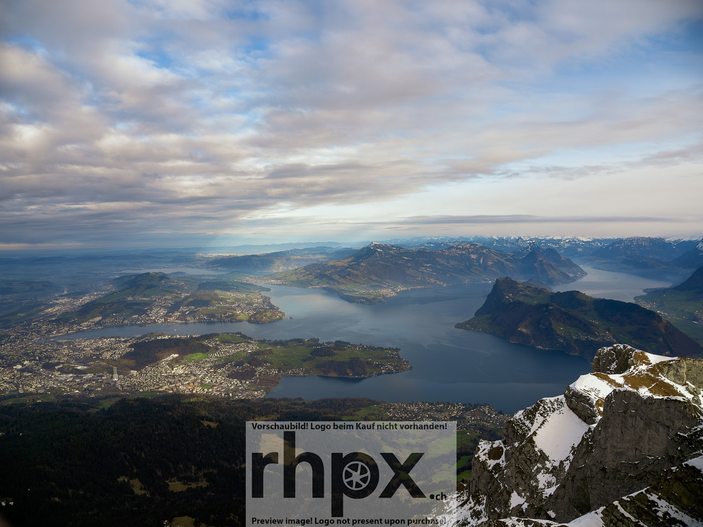 Panorama über den Vierwaldstättersee | See. Weite. Horizont.Vom Gipfel des Pilatus schweift der Blick über das verzweigte Blau des Vierwaldstättersees und die angrenzenden Täler. Die markante Topografie der Zentralschweiz zeigt sich hier in ihrer ganzen, beeindruckenden Vielfalt unter einem weiten Wolkenhimmel.Wähle unter "Produktauswahl" dein Wunschformat: Vom klassischen Wandbild über Puzzle &amp; Tassen bis zum digitalen Download (z.B. als Handy-Hintergrund). - Realisiert mit Pictrs.com