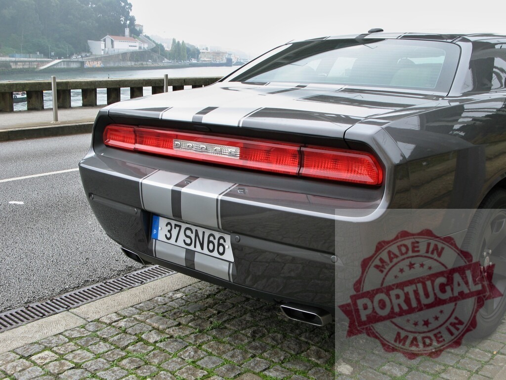 Dodge Challenger muscle car parked along riverside | Dodge Challenger sports coupe with racing stripes parked on a cobbled street by a river - Realisiert mit Pictrs.com