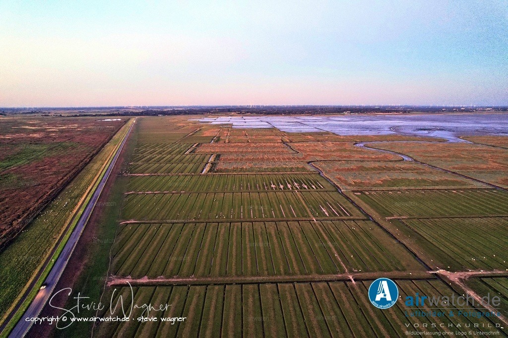 DJI_0686 | Historisch wurde die Verbindung in mehreren Schritten realisiert: 1906/07 wurde zunächst ein niedriger, nicht befahrbarer Damm zum Küstenschutz errichtet, den Fußgänger bei Niedrigwasser überqueren konnten.  Der hochwasserfreie, autogerechte Ausbau erfolgte zwischen 1933 und 1935, wodurch die Insel unabhängig von den tideabhängigen Schiffsverbindungen wurde.  Seit der Fertigstellung des Beltringharder Kooges im Jahr 1987 ist Nordstrand eine von drei Seiten vom Meer umgebene Halbinsel, wobei der Damm heute die südliche Flanke dieses Koogs bildet.