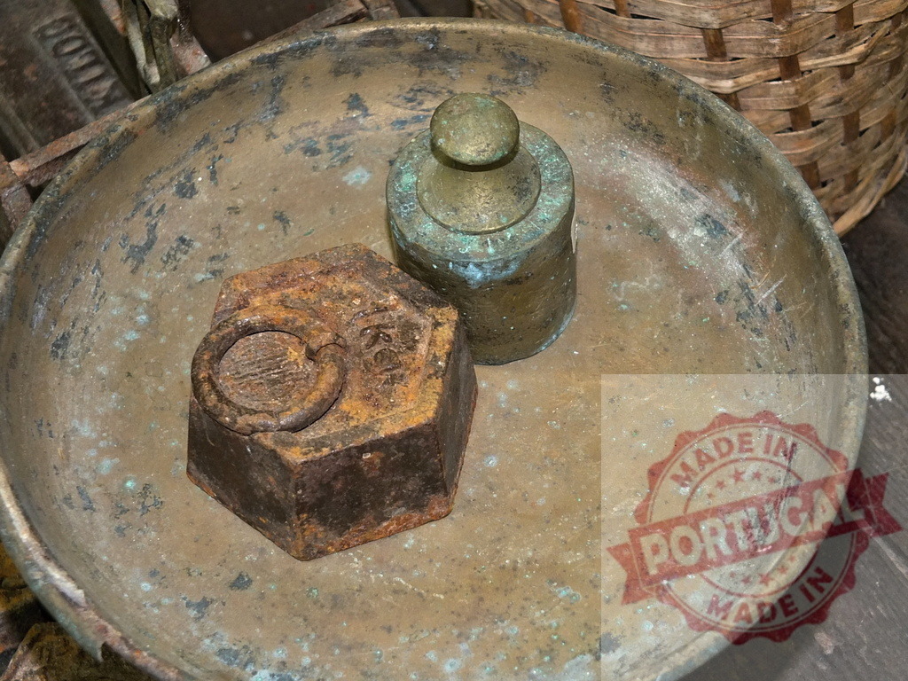 Ancient rustic weights resting on old brass scale pan | Antique measuring weights in a weathered brass pan, showing age and texture - Realized with Pictrs.com
