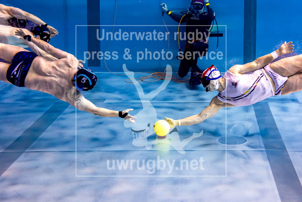 Deutsche Meisterschaft 2024 in Unterwasser-Rugby | Halbfinale: TC Bamberg in weiß gegen desn TSV Malsch in blau. Der Bamberger Christian Kempf gewinnt das Anschwimmen zum Beginn des Spieles und ist als erster am Ball, welcher in der Mitte des Spielfeldes auf dem Boden liegt. - Realisiert mit Pictrs.com