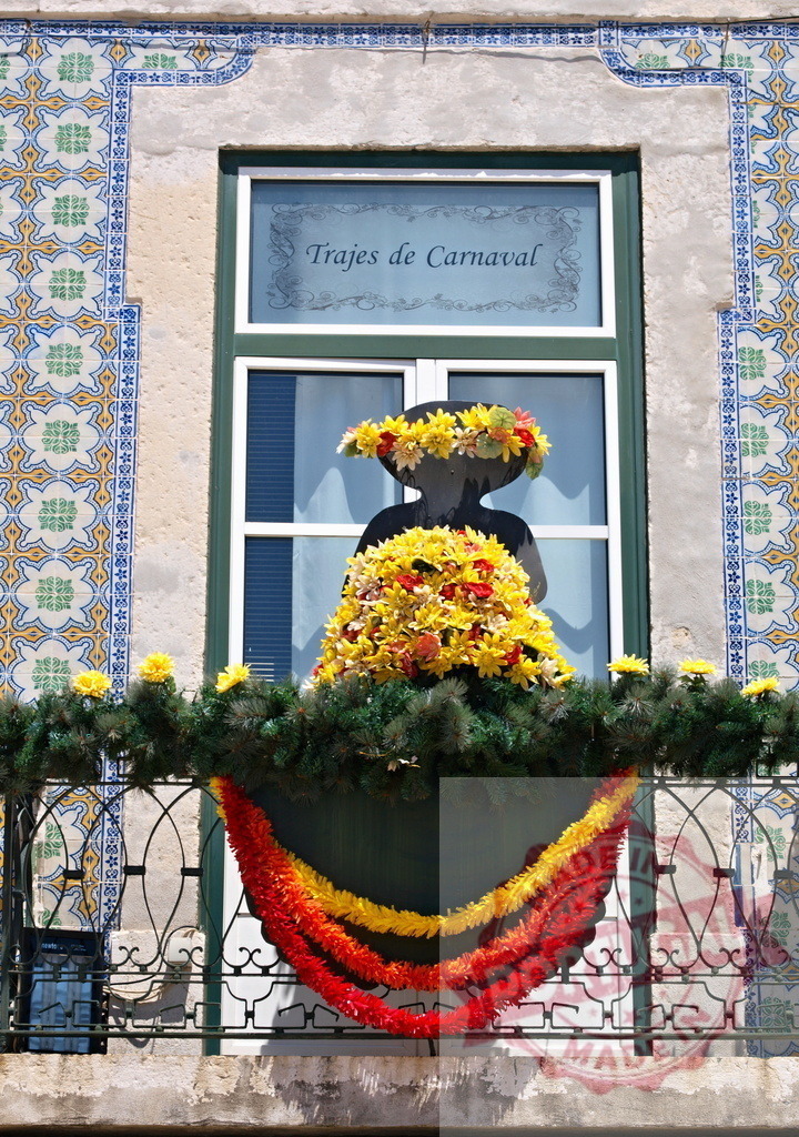 Carnival decoration on a balcony with Trajes de Carnaval sign | Balcony decorated with a silhouette, flowers, garlands, and Portuguese tiles for Carnival - Realisiert mit Pictrs.com
