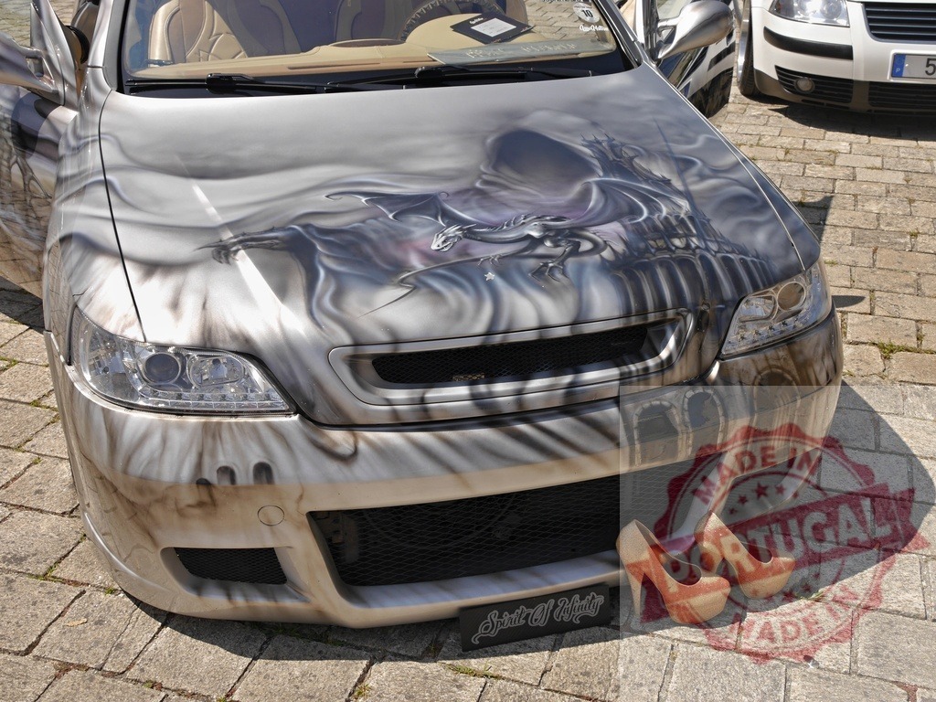 Custom car showing airbrush dragon castle art | Customized car body featuring elaborate airbrush artwork of a dragon and castle, with high heels beside it - Realized with Pictrs.com