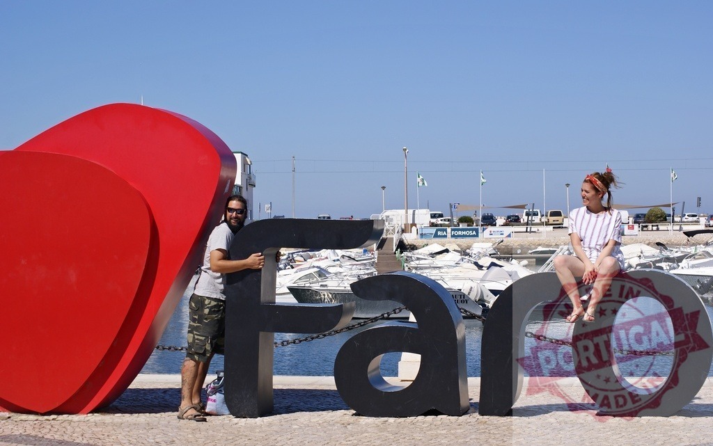 Couple interacting with I love Faro sign at marina | Young couple posing with the I love Faro sign overlooking the marina on a sunny day - Realized with Pictrs.com
