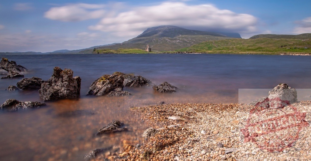 Ardvreck Castle ruins reflecting history in Loch Assynt | Ardvreck Castle ruins standing by Loch Assynt under a cloud-kissed mountain - Realized with Pictrs.com