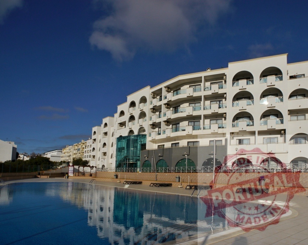 Resort hotel building with outdoor swimming pool | Resort hotel building reflecting in an outdoor swimming pool under a clear blue sky - Realisiert mit Pictrs.com