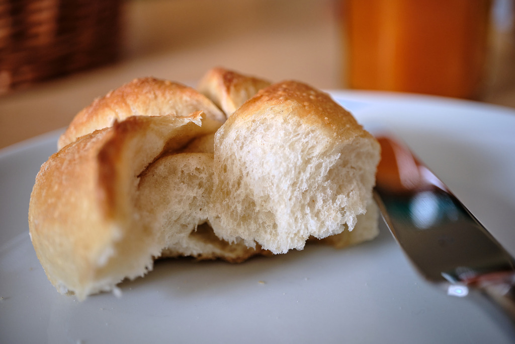 gebrochener Bäckersemmel auf dem Teller | Wien, Austria - March 30, 2023: gebrochener Bäckersemmel auf einem Teller, im Hintergrund eine Marmelade. - Realisiert mit Pictrs.com