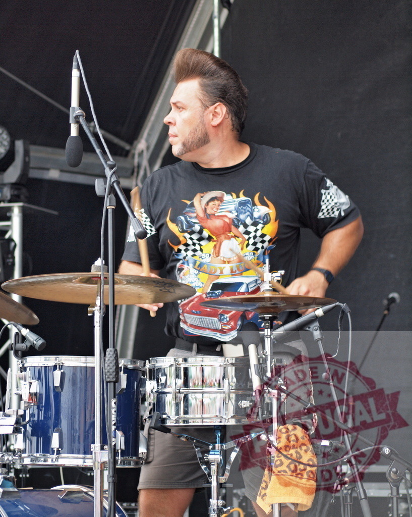Rockabilly drummer performing live at music festival | Musician with pompadour hairstyle playing drums during a concert - Realisiert mit Pictrs.com