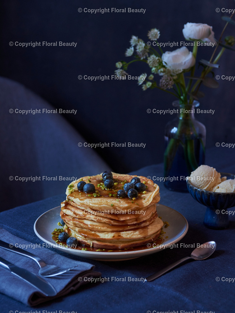 Pancakes mit Blaubeeren und Ahornsirup | gestapeltet Pancakes mit Blaubeeren, Ahornsirup und Pistazien mit Vanilleeis auf dunkler Tischdecke - Realized with Pictrs.com