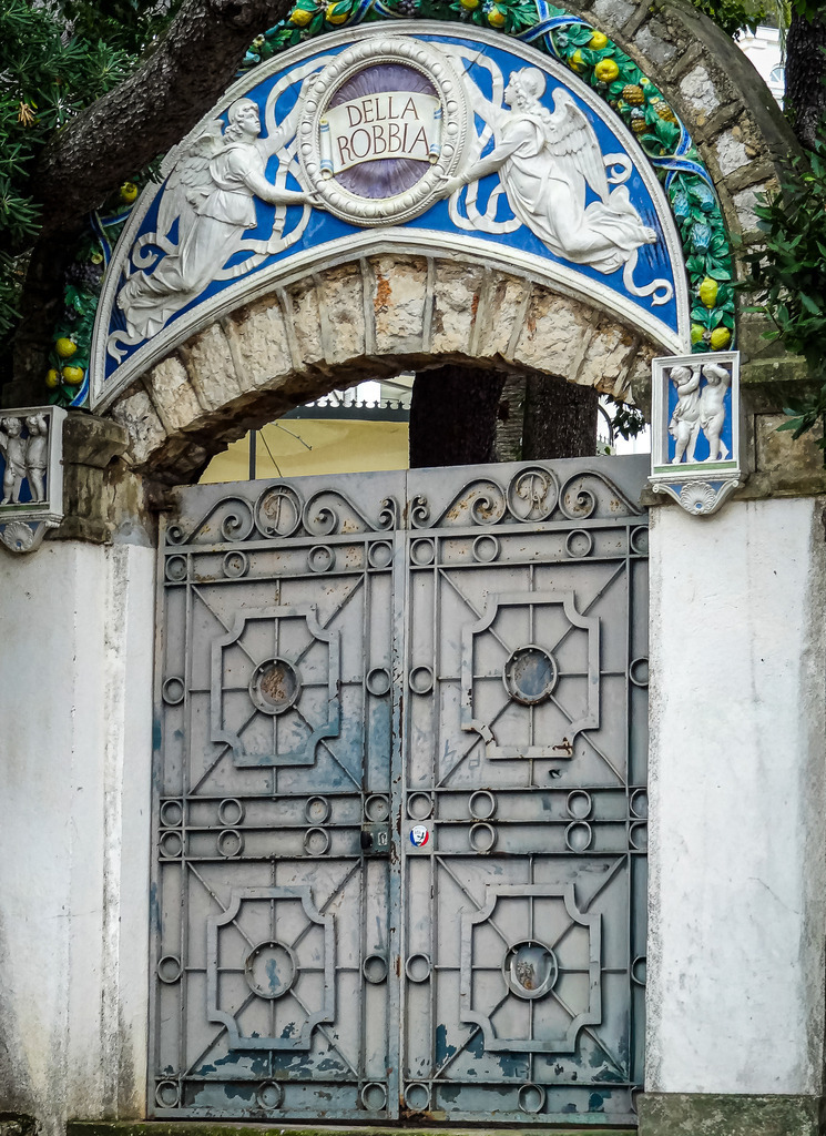 Wandbild Kunstdruck Poster – Tor zur Côte d'Azur: Exklusiver Villen-Eingang in Cap-Ferrat | Hol dir den prachtvollen Luxus und die historische Eleganz der französischen Riviera direkt in deine Wohnräume. Diese beeindruckende Architekturfotografie fängt den kunstvollen Eingang einer historischen Villa auf der legendären Millionärsinsel Saint-Jean-Cap-Ferrat ein. Das faszinierende, reich verzierte Tor im klassischen „Della Robbia“-Stil besticht durch seine meisterhaften Steinmetz-Reliefs und Skulpturen. Umrahmt von mediterranem Grün strahlen die warmen Natursteintöne eine zeitlose Exklusivität und majestätische Ruhe aus, die jeden Raum optisch aufwertet.Dieses luxuriöse und harmonische Kunstwerk ist der perfekte, stilvolle Blickfang für ein modernes Wohnzimmer, das repräsentative Büro, ein helles Design-Loft oder für eine einladende, elegante Atmosphäre im Flur.Um die immense Detailtiefe der Ornamente und die feine Textur des historischen Steins perfekt zur Geltung zu bringen, empfehle ich den Druck auf unseren Premium-Materialien: Erlebe maximale Plastizität und Tiefenwirkung auf edlem Acrylglas, ein hochmodernes, absolut edles Finish auf robustem Alu-Dibond oder klassischen Galerie-Charakter auf einer matten Leinwand. Bring exklusives Urlaubsflair an deine Wand! - Realisiert mit Pictrs.com