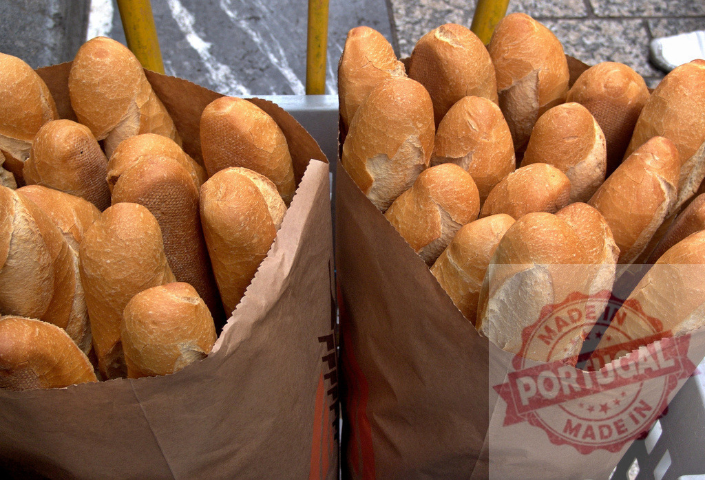Freshly baked baguettes filling paper bags for sale | Long baguettes with golden crusts standing upright in two brown paper bags - Realisiert mit Pictrs.com